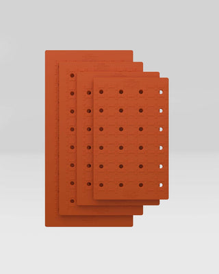Cushy Ride™ Kennel Pad in orange, showcasing four sizes stacked for superior canine comfort.
