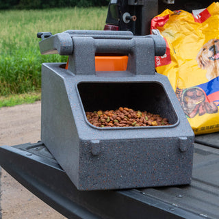 Open Chow Box™ filled with dog food, positioned on a truck bed with grassy background, highlighting its spacious capacity.